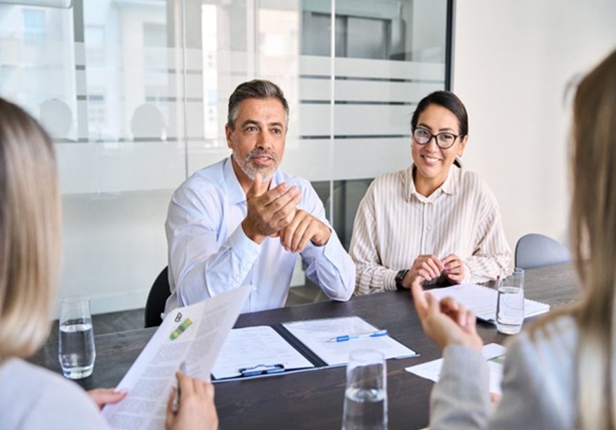 Group of business professionals in a meeting, discussing strategy and collaboration in a modern office setting.